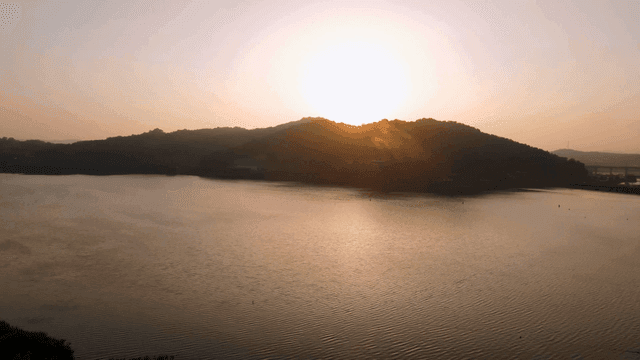 Tranquil lake where sun rises over hill