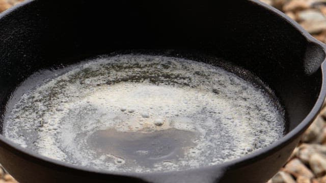 Cooking garlic and bacon slices in a heated hot frying pan