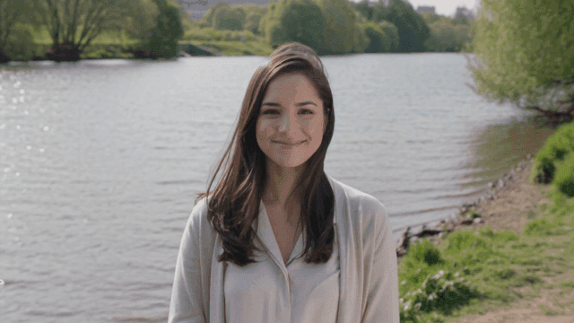 White woman smiling and looking straight ahead by river