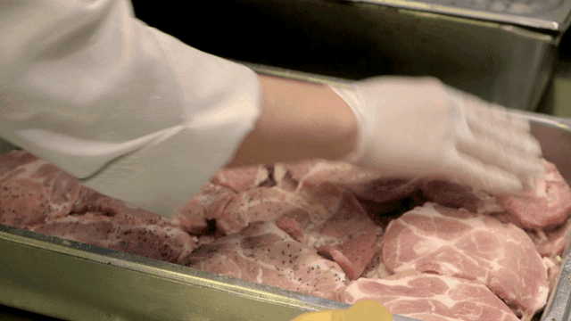 Raw meat sprinkled with pepper in kitchen