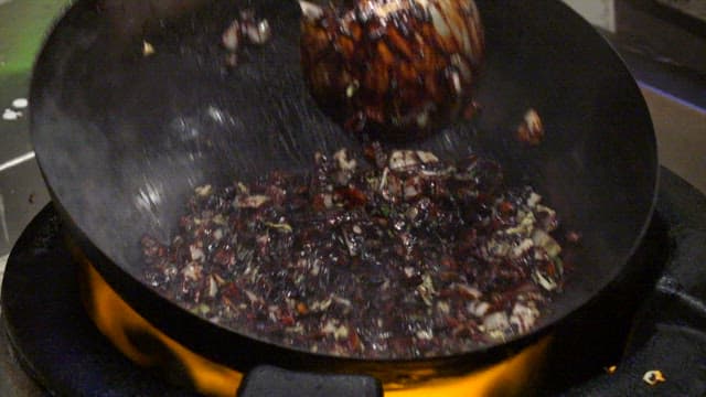 Stir-frying meat and vegetables in a wok with black bean paste