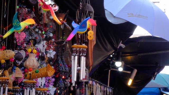 Colorful handcrafted wind chimes displayed at an outdoor street market stall