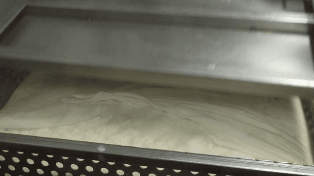 Tofu being pressed in a metal container