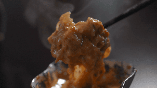 Chopsticks dipping meat into peanut sauce for cheese mala hot pot