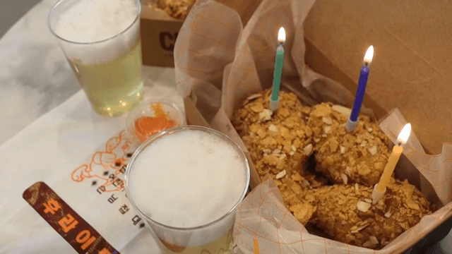 초가 꽂힌 치킨 모양의 떡과 빵 그리고 맥주