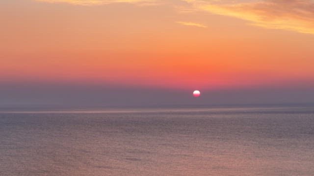석양이 지는 붉은 하늘 아래 평온한 바다