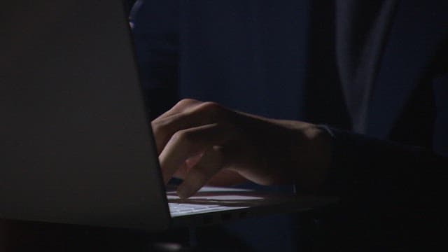 어두운 조명 아래에서 노트북을 사용하는 사람