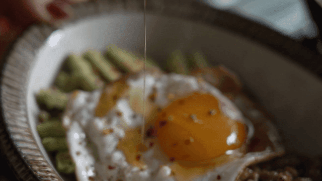 A fried egg with avocado and grains