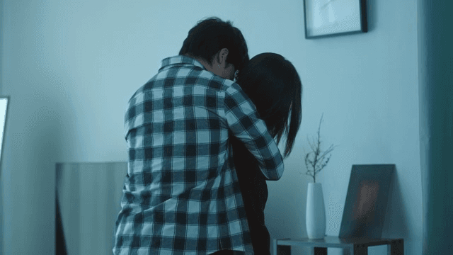 Man hugging woman in messy living room