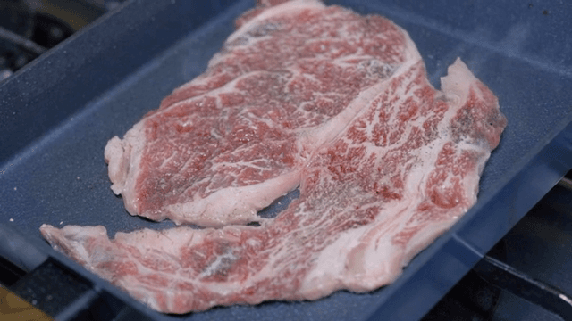Raw marbled steak on a grill pan
