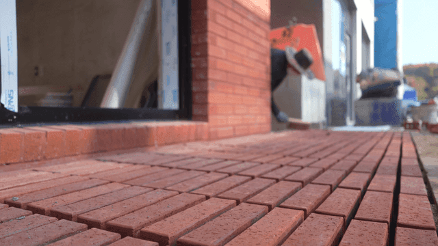 Workers laying bricks outside a building