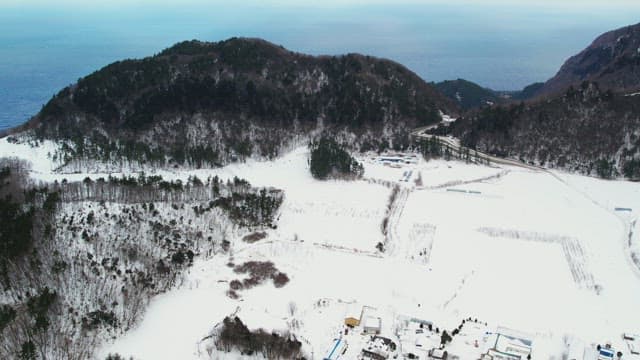 눈 덮인 산 너머의 푸른 하늘과 바다