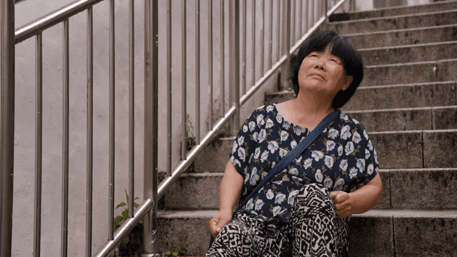 계단에 앉아 다리를 두드리는 노인 여성