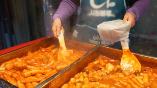 매콤한 떡볶이를 그릇에 담아주는 시장 상인