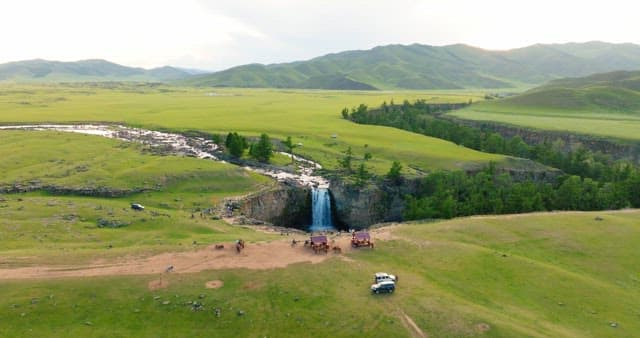 Scenic waterfall in a vast green landscape