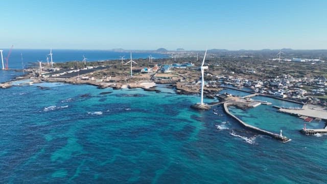 Coastal town with wind turbines by clear blue sea