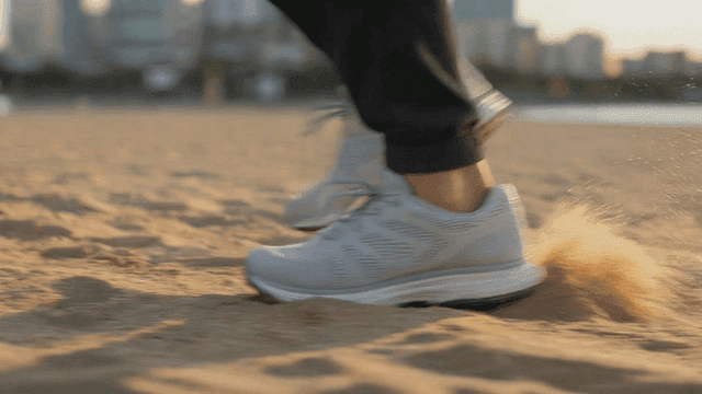 Shoes walking on sand at sunset