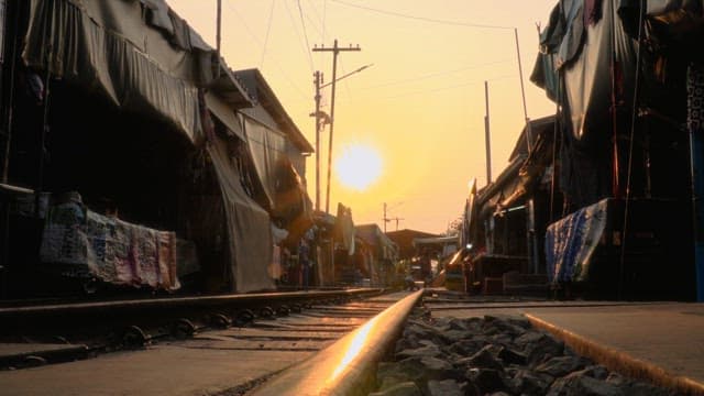 해 질 무렵 철로를 따라 분주한 골목을 걷고 있는 사람들