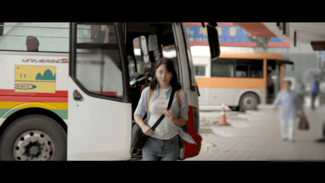 Woman wearing earphones getting off at bus stop