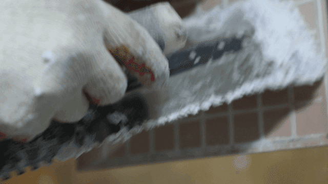 Worker applying adhesive on a tile surface