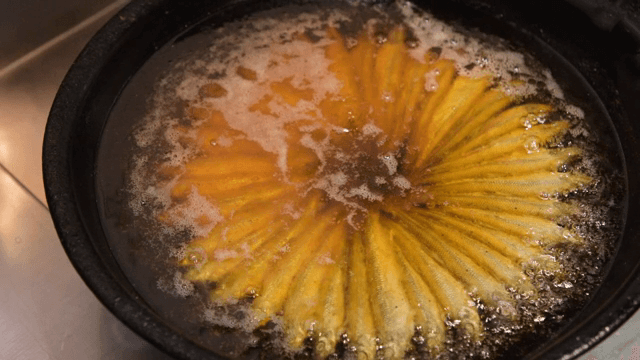 팬에서 뜨거운 기름에 생선 튀기기