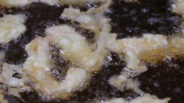 주방에서 뜨거운 기름에 음식을 튀기는 장면