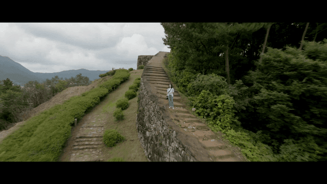 Woman holding camera standing on ancient stone steps
