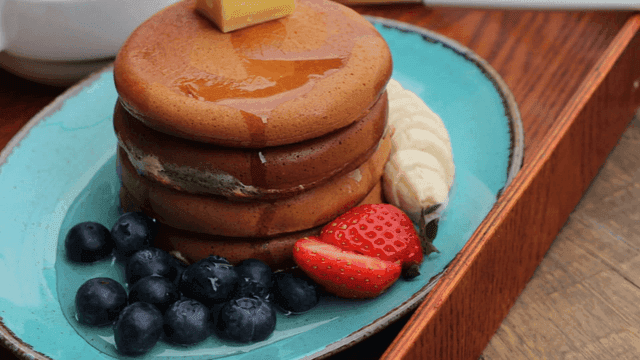 과일과 함께 제공되는 버터와 시럽을 얹은 팬케이크