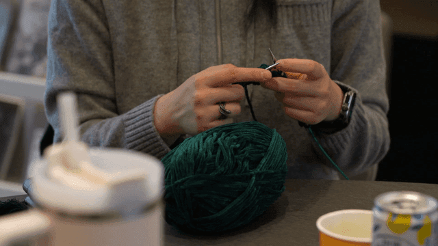 녹색 실로 뜨개질하는 사람