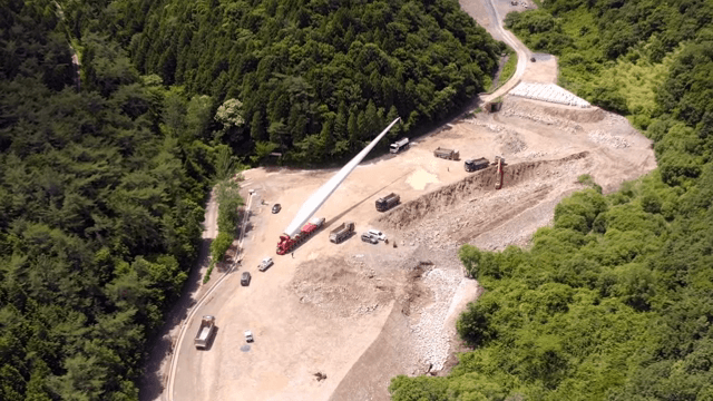 산 속 공사현장에서 풍력 터빈 자재를 운반하는 모습