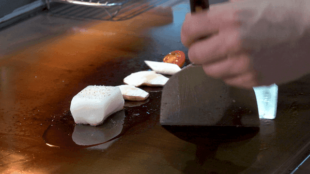 Dish of sea bass fillets and matsutake mushrooms stir-frying on hot grill