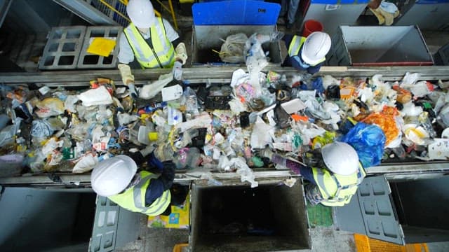 Workers sorting through waste on a conveyor belt