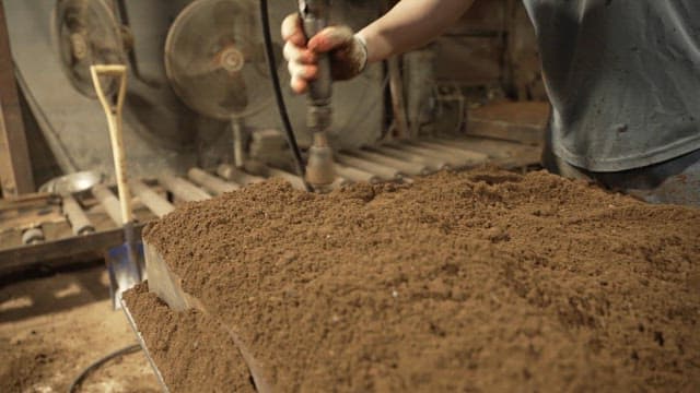 Worker using a tool on a sand mold