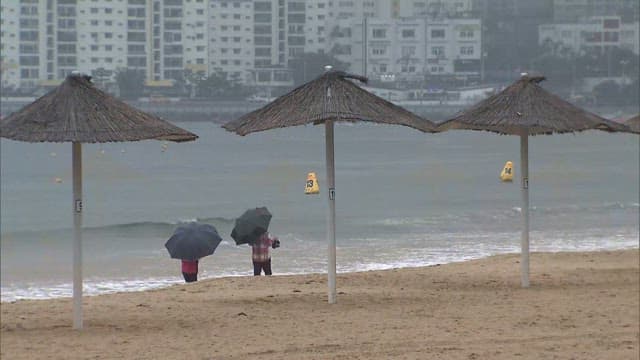 People with Umbrellas on the Beach on a Rainy Day