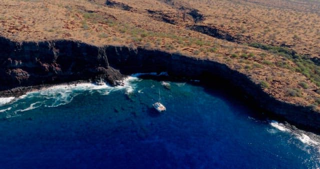 Aerial view of a boat near a coastal cliff