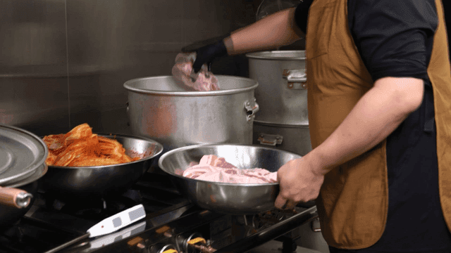 Chef preparing kimchi stew with pork in kitchen