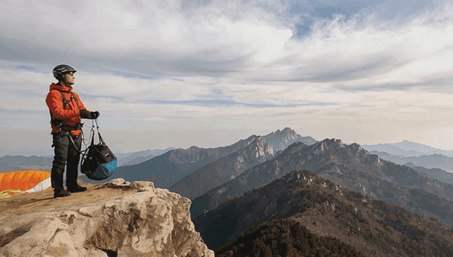 산 정상에서 패러글라이딩 준비하는 사람들