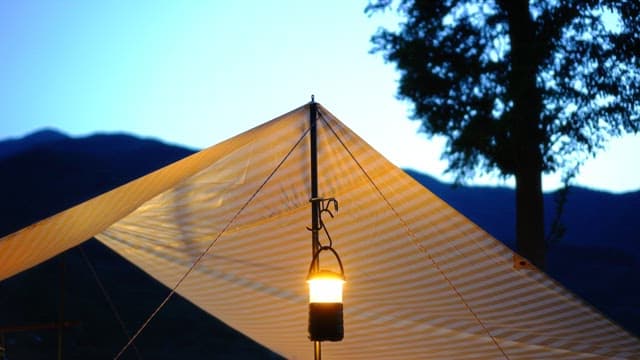 Nighttime scene with a lantern hanging under a tent