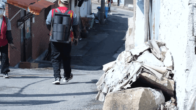 People carrying briquettes on their backs through narrow alleyways