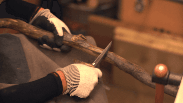 Person carving a wooden stick indoors