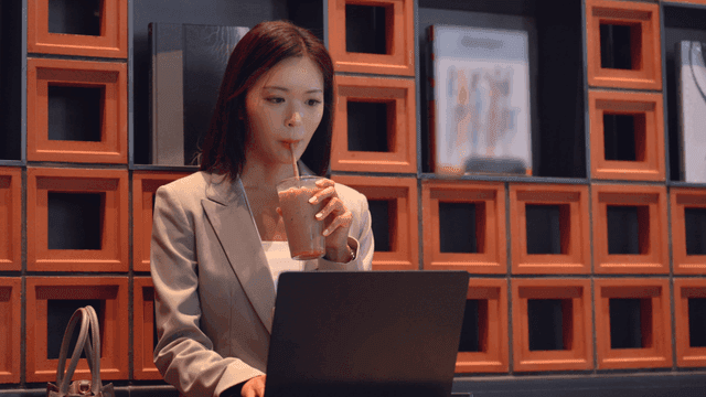 Working woman working on laptop while drinking coffee at cafe