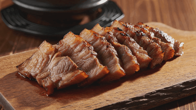 Sliced grilled pork belly on a wooden board