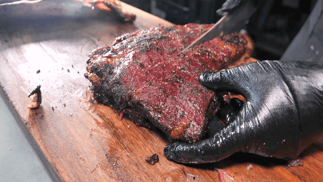 Texas barbecue being cut on wooden cutting board