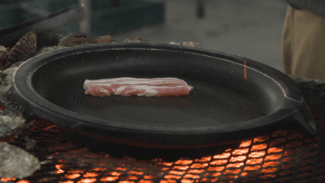Person grilling pork belly on grill
