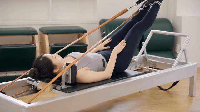 Woman practicing pilates on a reformer