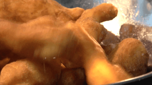 그릇에 옮겨지는 갓 튀겨진 꽈배기들