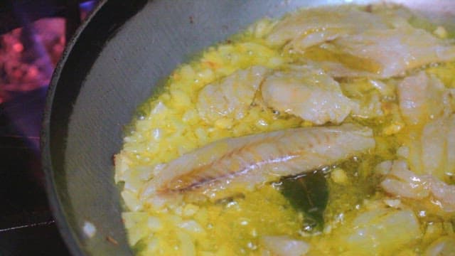 뜨거운 기름을 두른 팬에 요리하는 마늘과 생선 필레