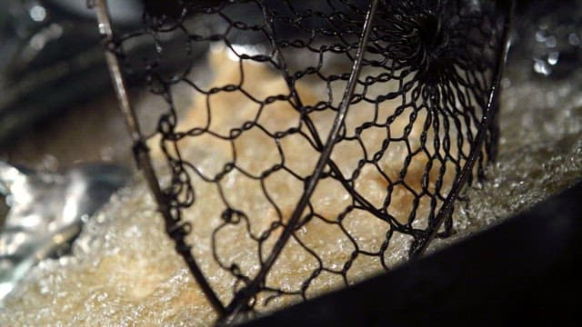 Frying meat in hot oil with a strainer