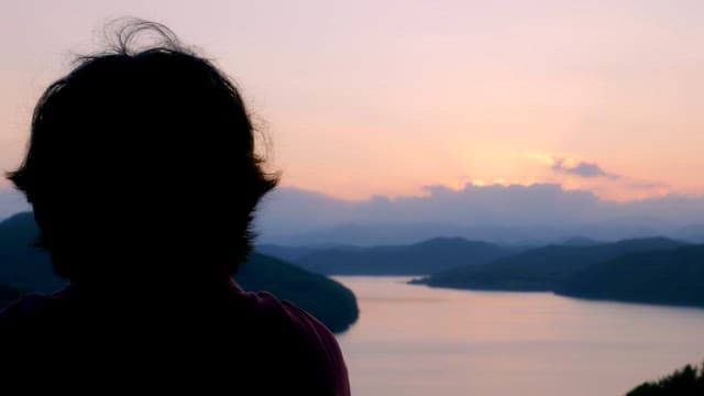 Person enjoying a serene lake view at sunset