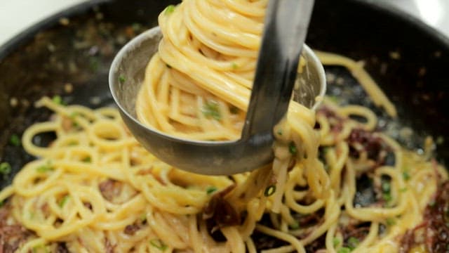 국자 위에서 젓가락으로 돌돌 말리는 크림 파스타